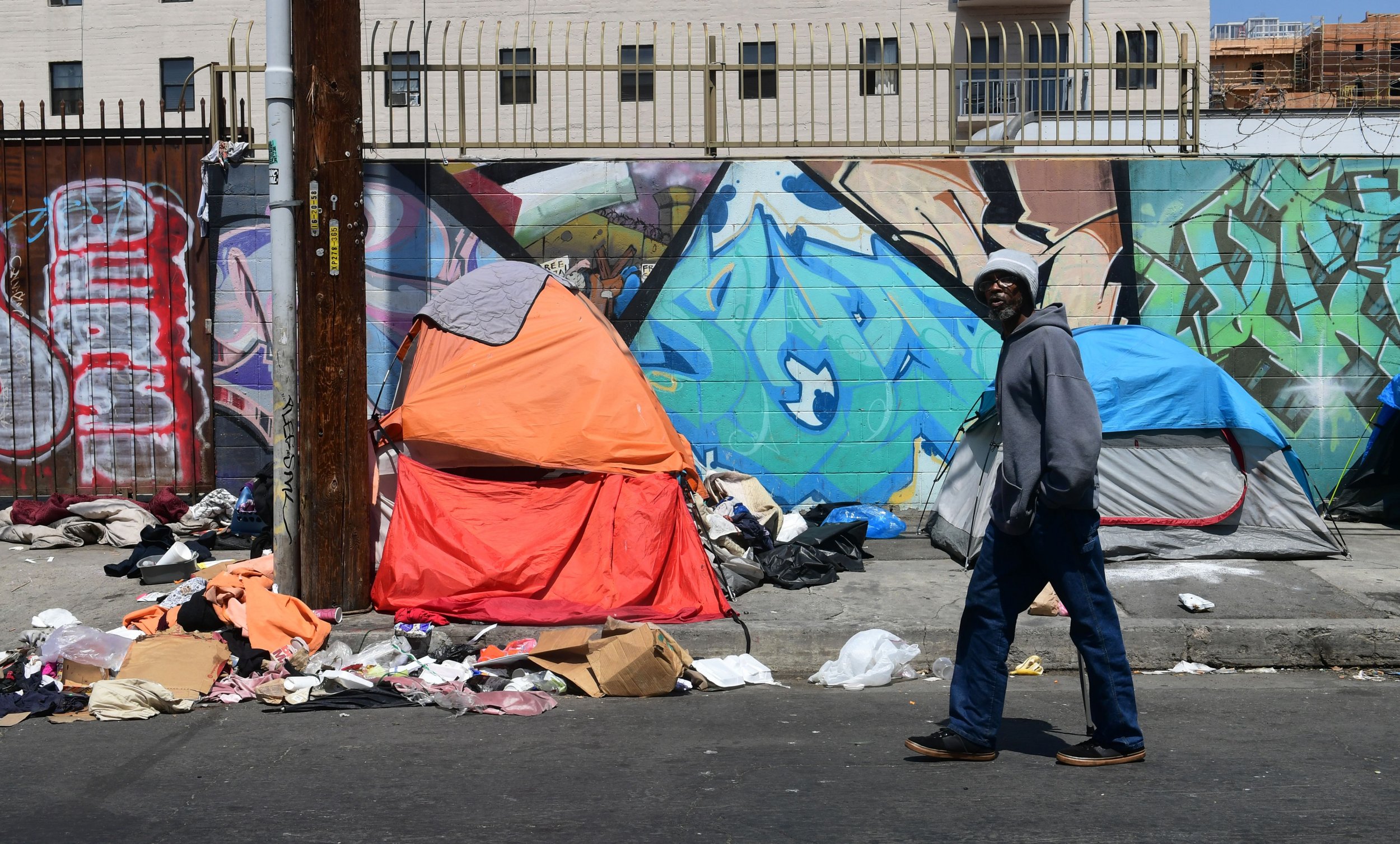 A pedestrian walks past tents and trash on a sidewalk in downtown Los Angeles on May 30, 2019.