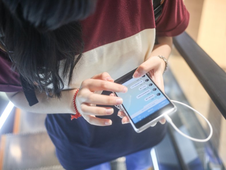 A girl chatting with WeChat on smartphone on a moving escalator in Japan
