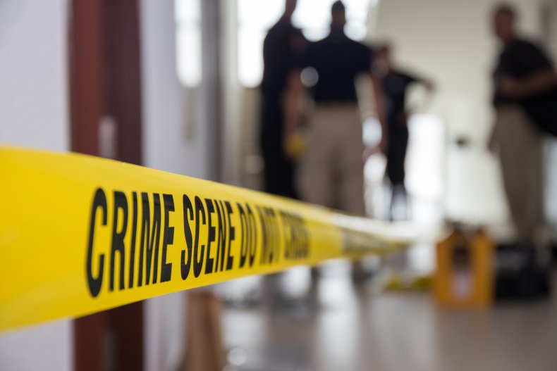 Crime scene tape in building with blurred forensic team