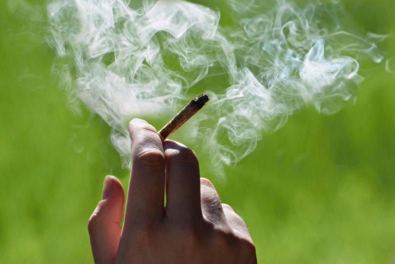 Hand holding a lit marijuana cigarette