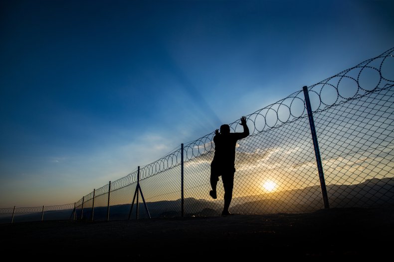 A man climbs a barbed wire fence