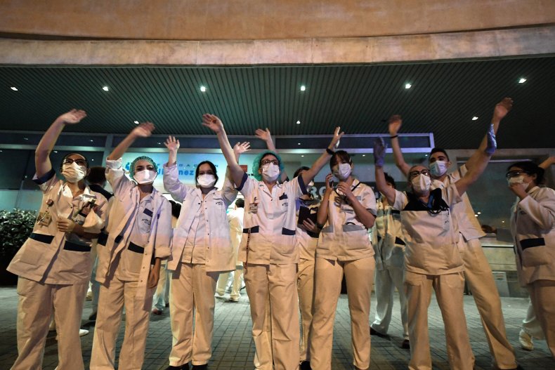 Healthcare workers dealing with the new coronavirus crisis wave in return as they are cheered on by people outside the Fundacion Jimenez Diaz hospital in Madrid on March 25, 2020.
