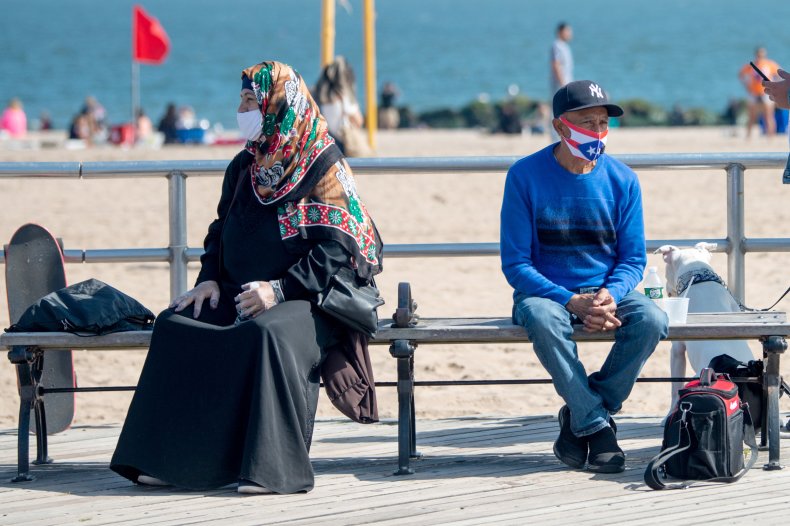 Two people sit on Coney Island boardwalk