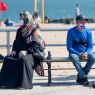Two people sit on Coney Island boardwalk