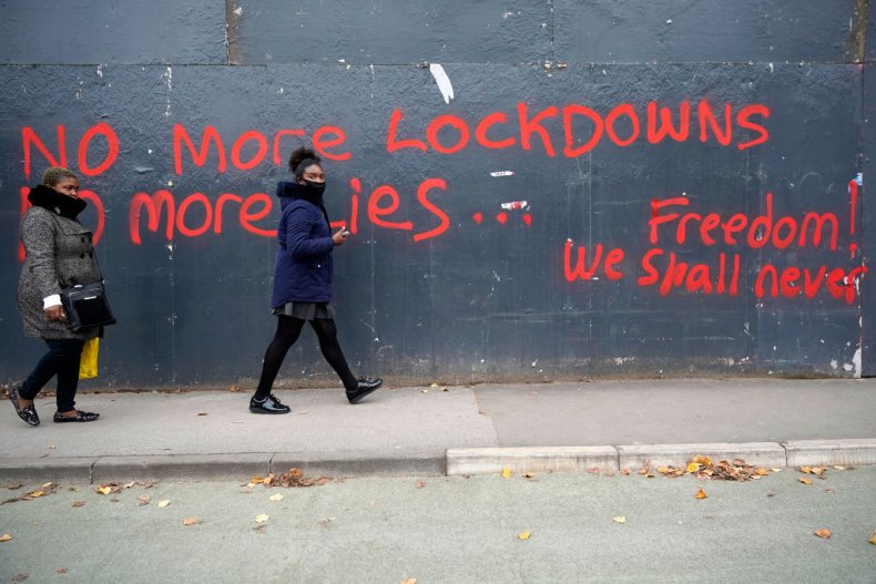 Women walk by anti-lockdown graffiti in Manchester