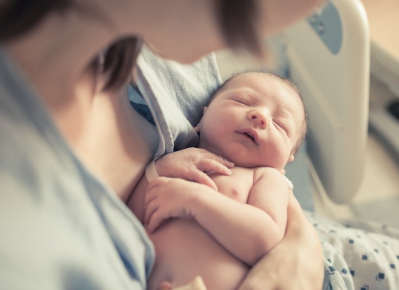 Newborn baby boy resting in mother's arms