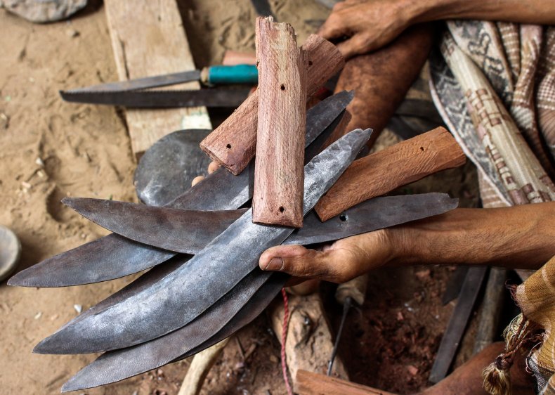 A person holds a handful of knives.