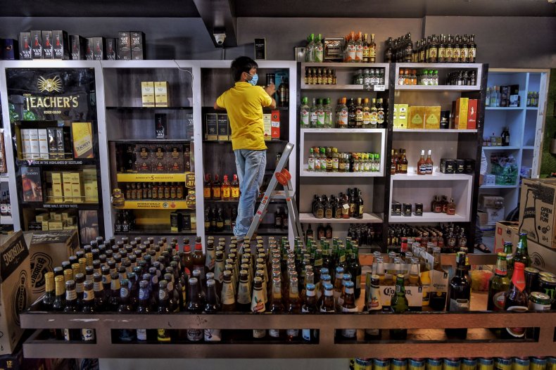 A man stocks liquor store shelves.