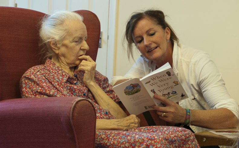 Carer reads to woman with dementia.