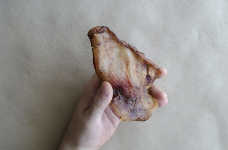 Man holding a dried pork ear.