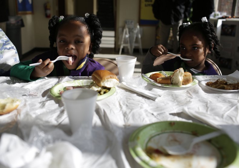 Two little Black girls eat a meal.