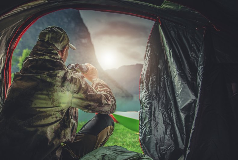 A hunter in his tent using binoculars