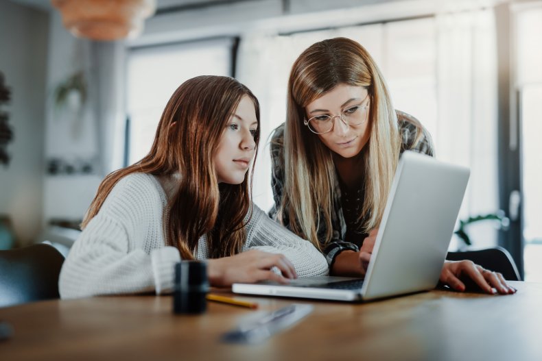 A woman and teen girl on laptop.