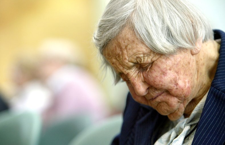 An elderly woman rests at a talk.