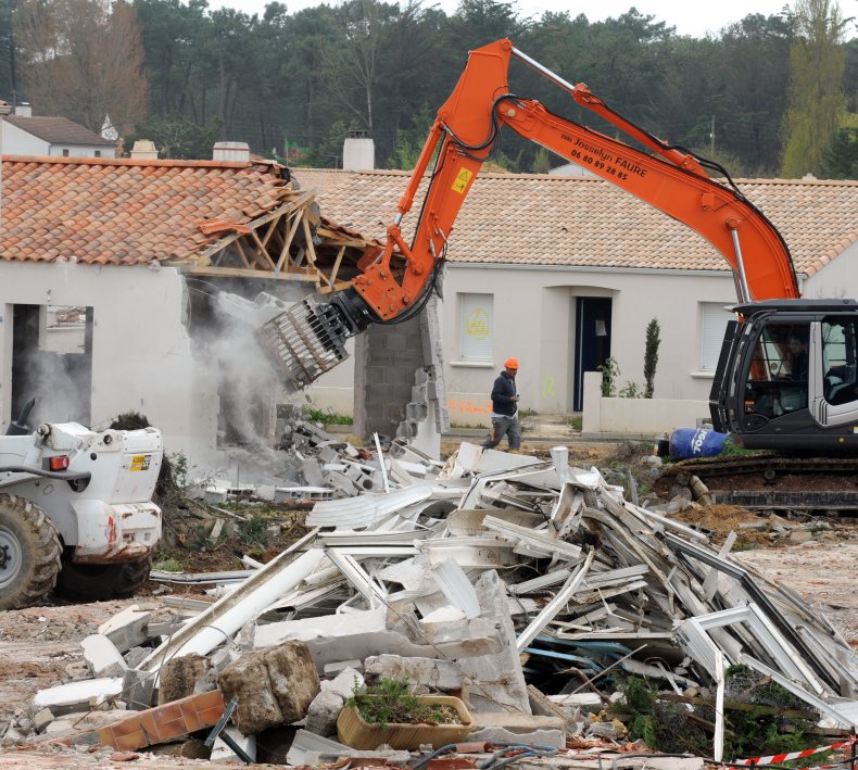 A backhoe demolishes a house in France.