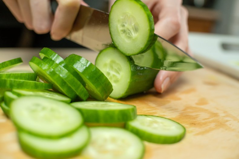 Stock image of someone chopping cucumber.