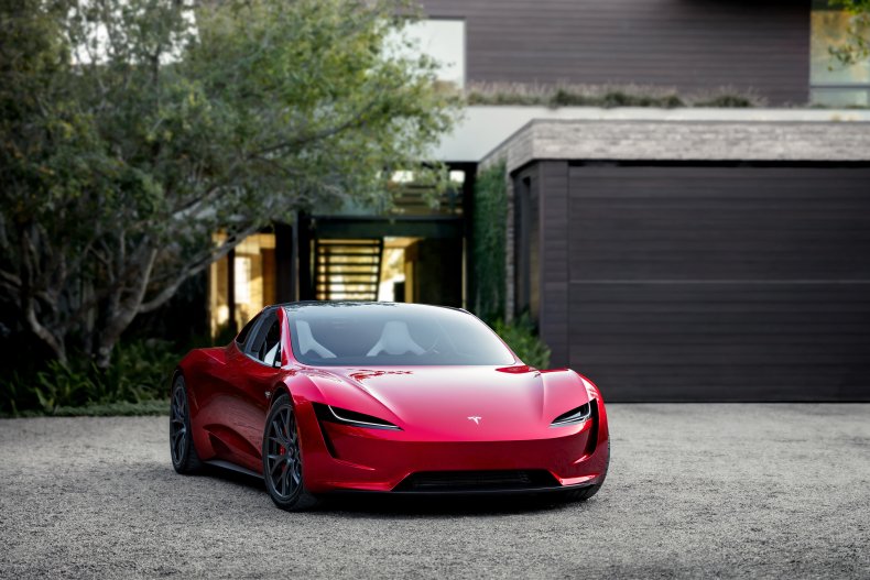 Tesla Roadster parked red house driveway