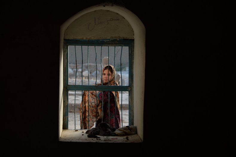 An Afghan girl looks through a window