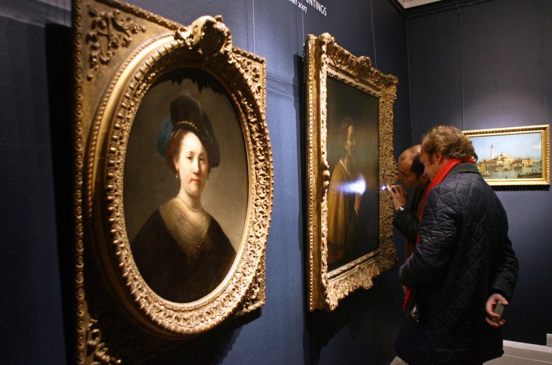 People examine a Rembrandt painting. 