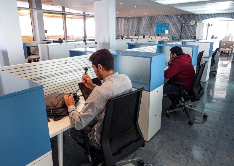 People sit in half-cubicles as they work