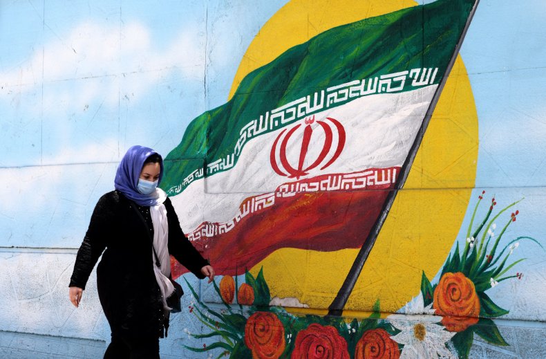 An Iranian woman walks past a mural
