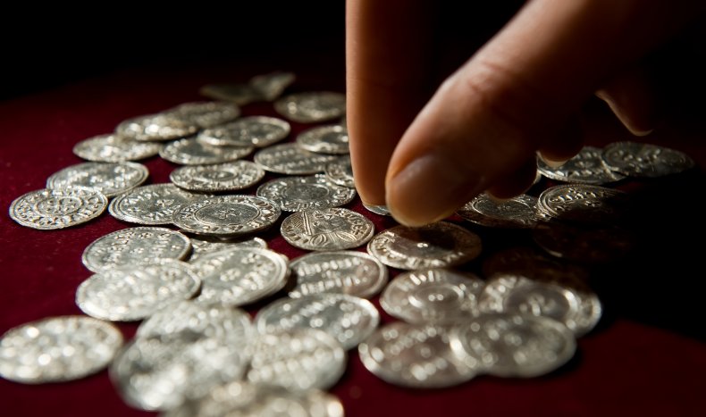 A person handles silver Viking-era coins.