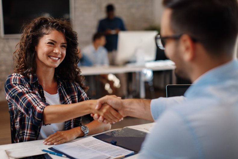 A woman shaking hands with a manager.