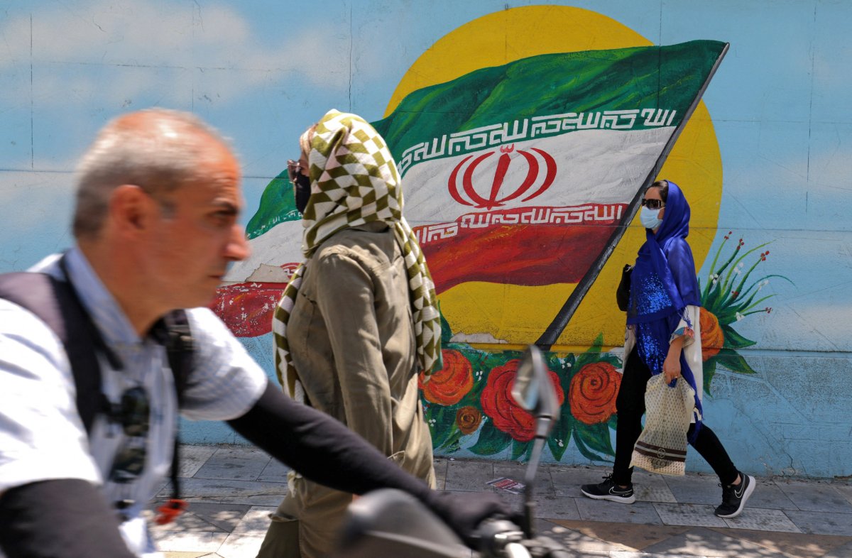 Iranians walk past a mural in Tehran