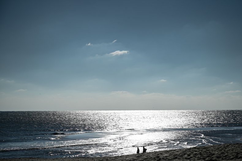A couple walks on a beach.