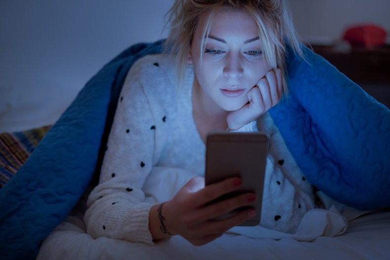 A woman in bed with a smartphone.