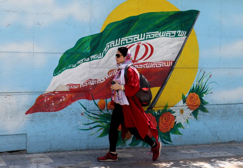An Iranian woman walks past a mural 