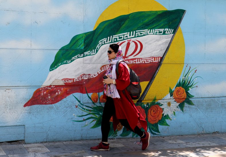 An Iranian woman walks past a mural