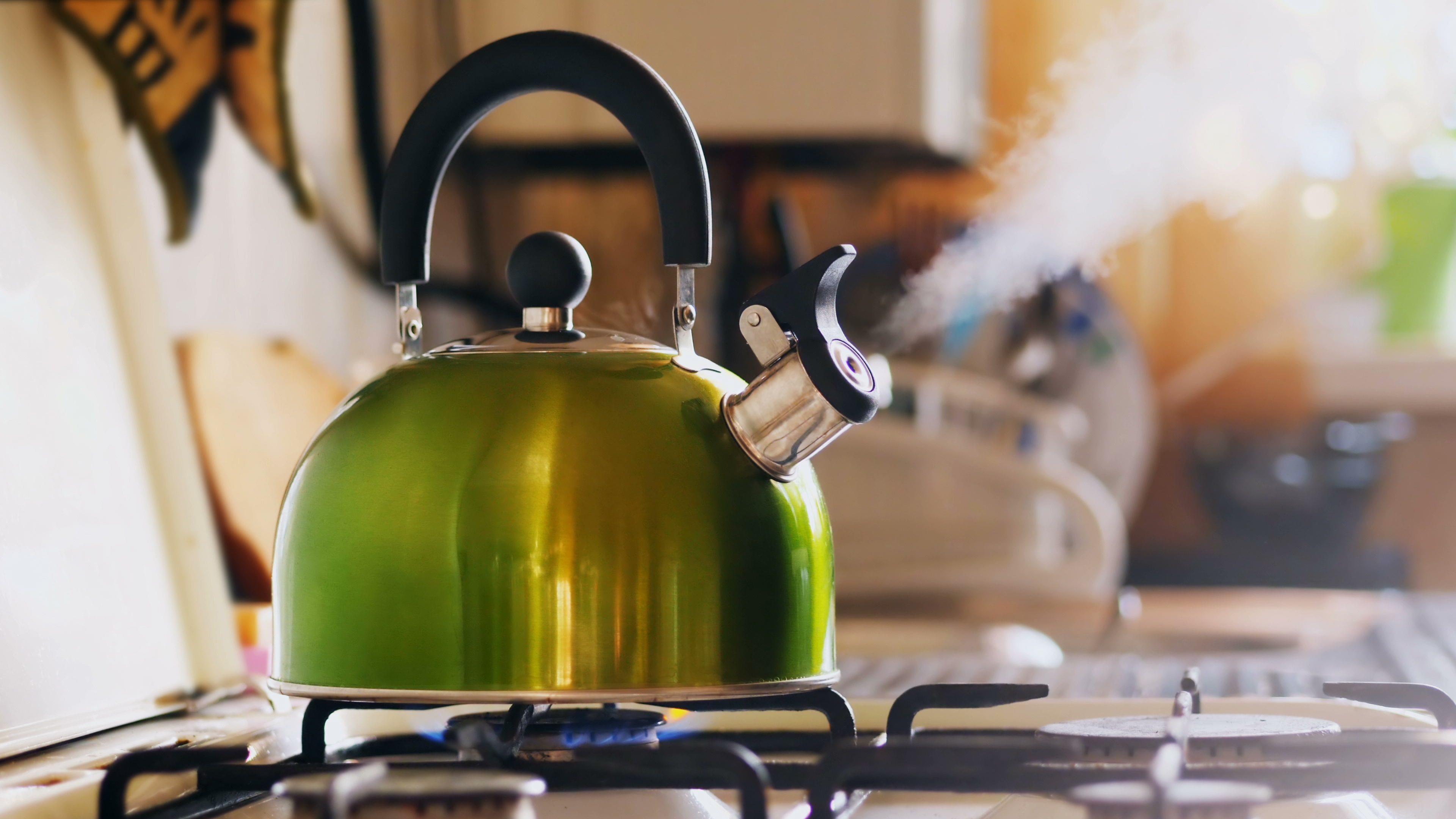 Green stove kettle on a stove boiling water