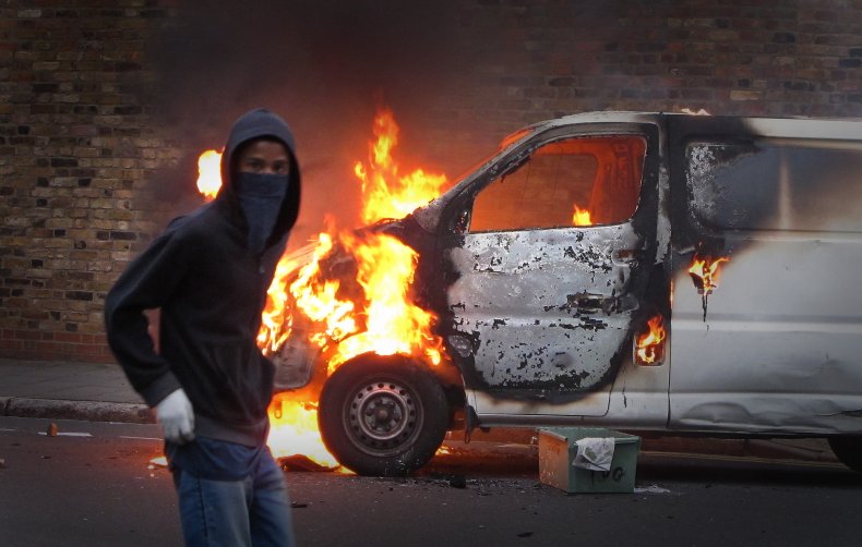 Rioter stands next to burning van