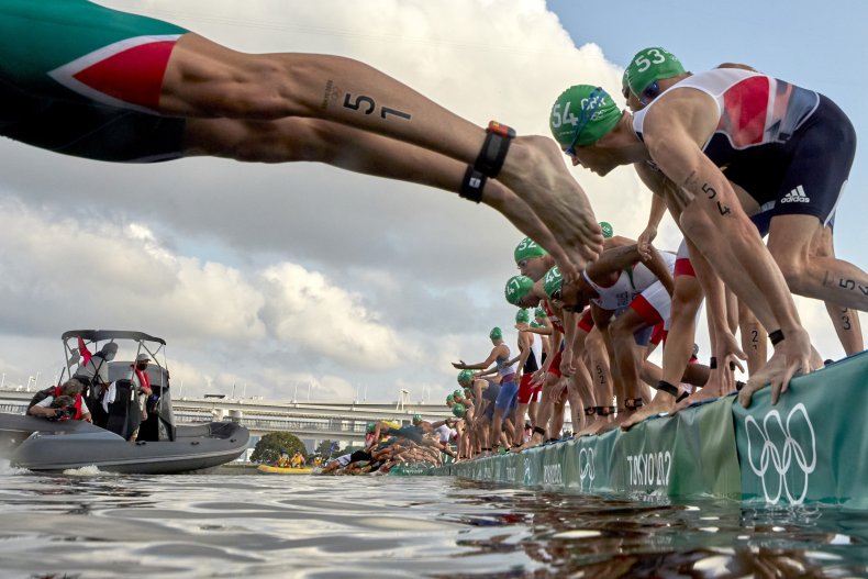 Triathletes dive into the water.