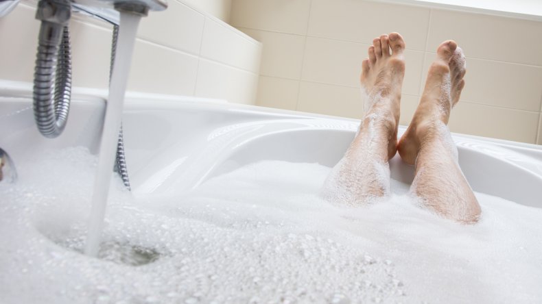 Man's feet rest at edge of bathtub