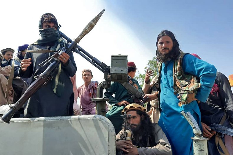 Taliban fighters sit over a vehicle.