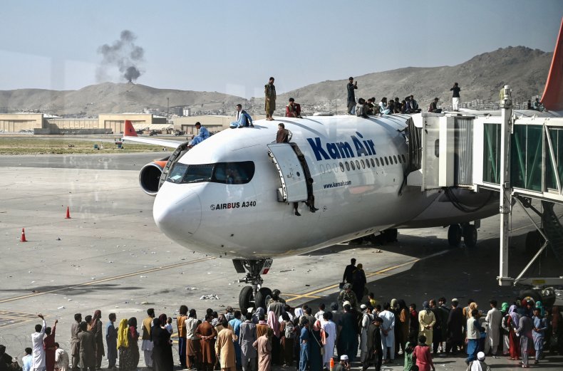 Afghan people climb atop plane