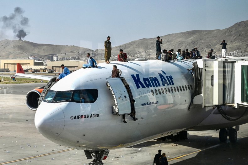Afghan people climb a plane to flee