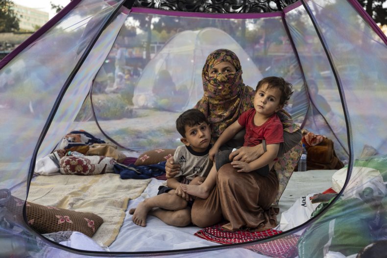 Displaced Afghan family sit in a tent