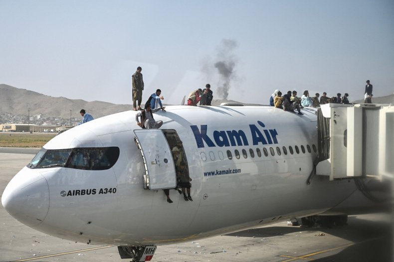 Afghan people climb atop a plane