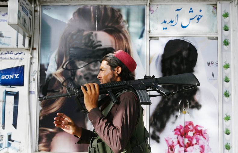 A Taliban fighter walks past a beauty