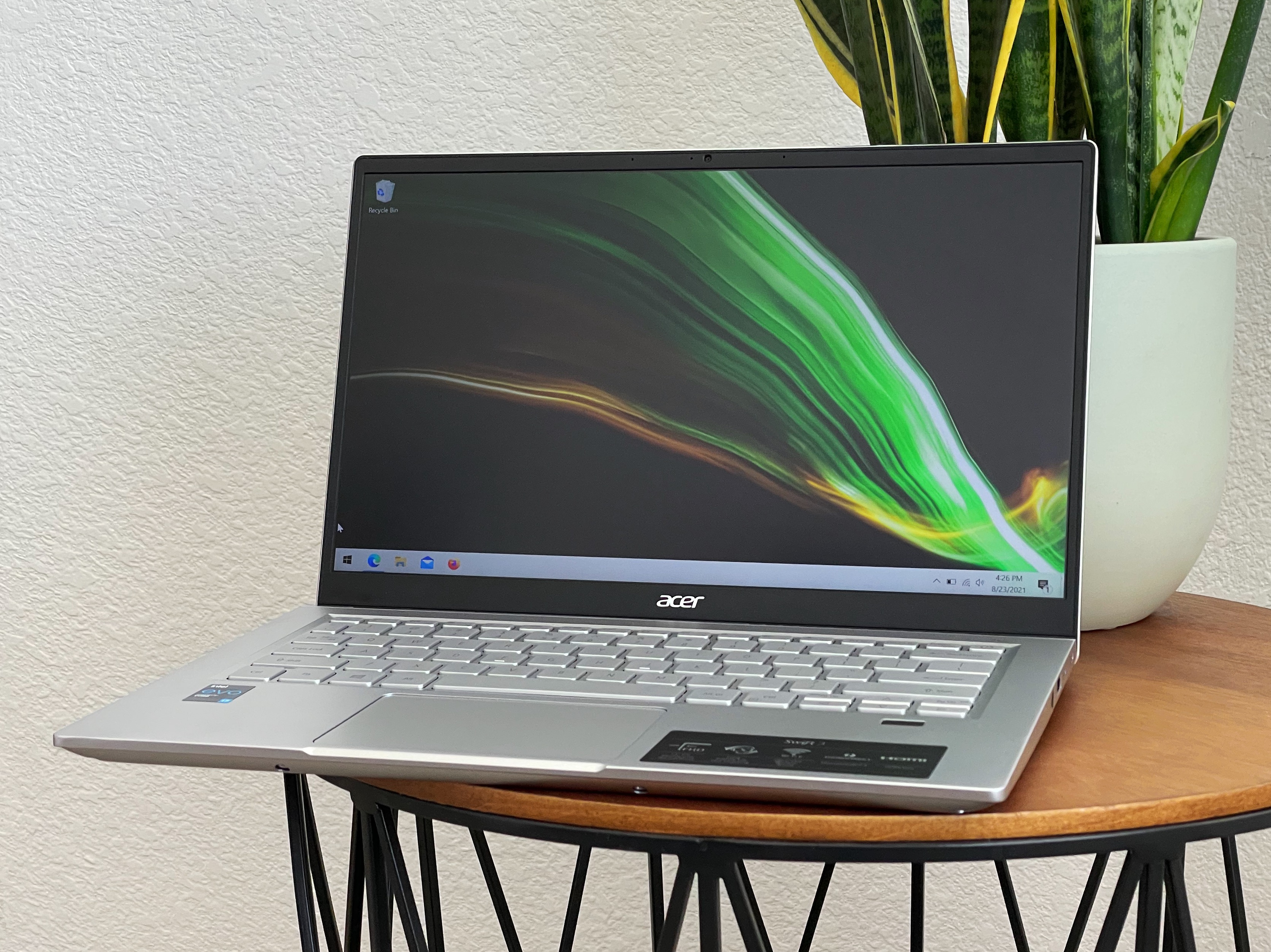  An Acer Swift 14 laptop sits on a table; the screen is on, and the keyboard is backlit.