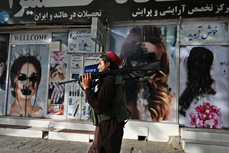 Taliban fighter walks past beauty salon