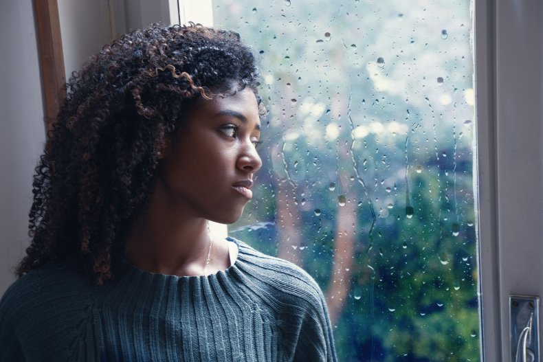 A worried woman looks out of window
