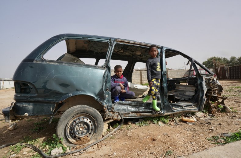Children pose in a destroyed car