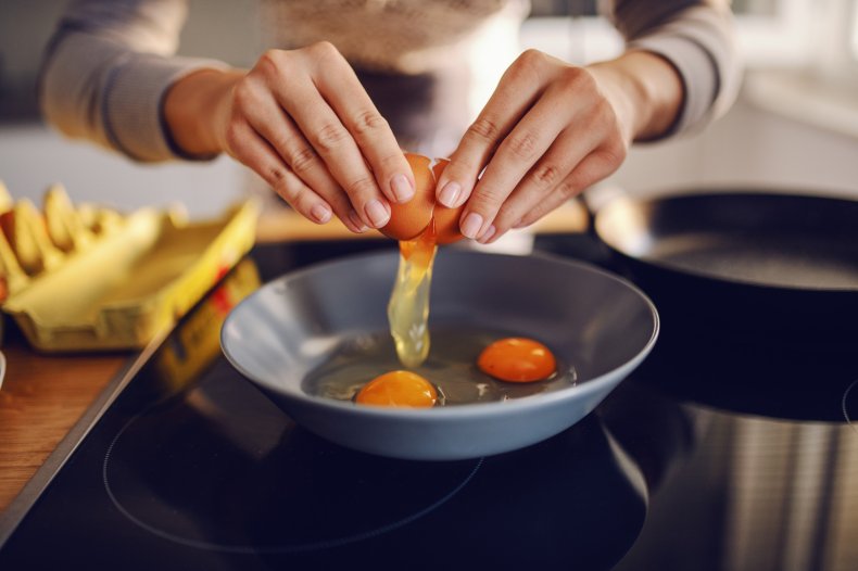 Hands cracking eggs in a pan