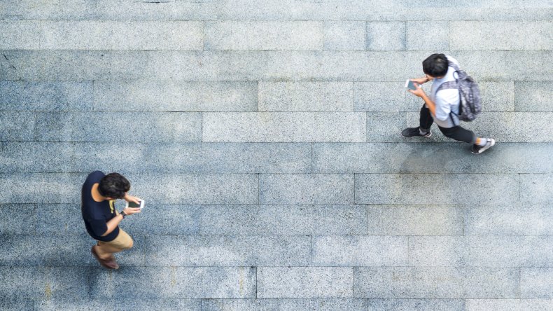 Two men walking looking at their phones