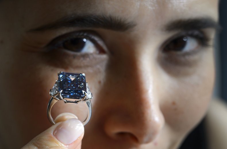 A woman holds up the "Oppenheimer Blue"diamond.