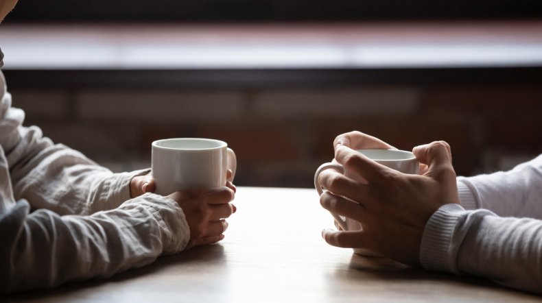 Couple sit opposite each other with coffee
